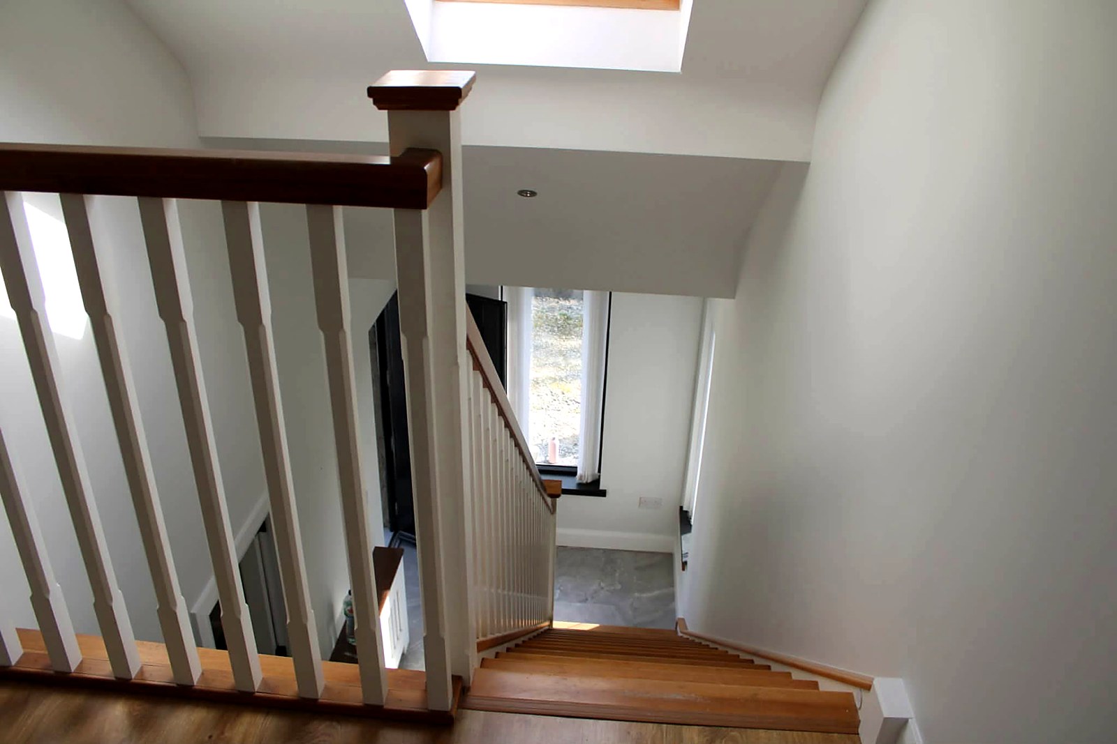 Landing looking down a stairwell with painted spindles and oak handrail