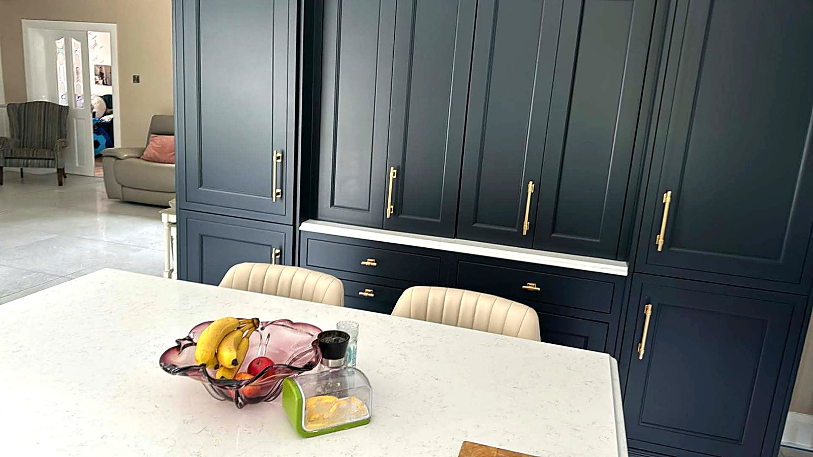 After: the same tall units resprayed deep navy with brass handles