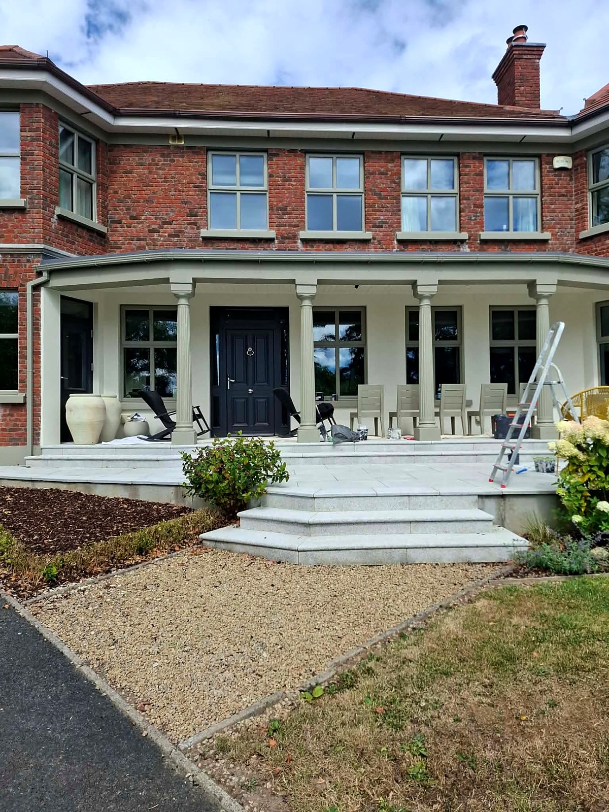 Painted porch with fluted columns, sage window frames and a deep navy front door